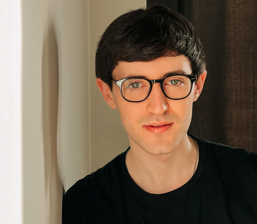 Foto von Matthew, der mit einem seriösen Blick und sanftem Lächeln in die Kamera blickt.