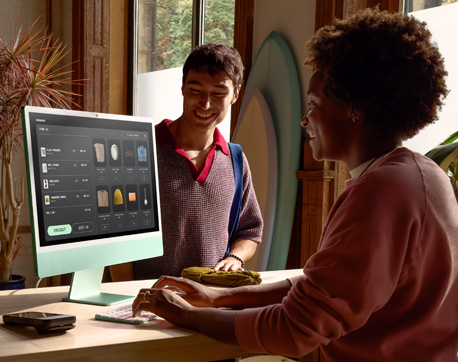 Dos personas en una habitación con mucha luz. Una mujer usando una iMac con pantalla de vidrio nanotexturizado y un hombre de pie, cerca de ella