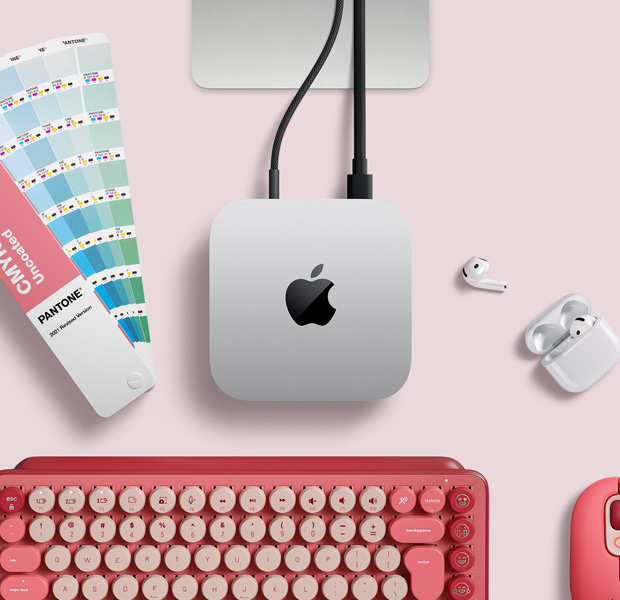 Pohled shora na stříbrný Mac mini v sestavě s AirPody, růžovou bezdrátovou klávesnicí, růžovou bezdrátovou myší a vějířovým vzorníkem barev