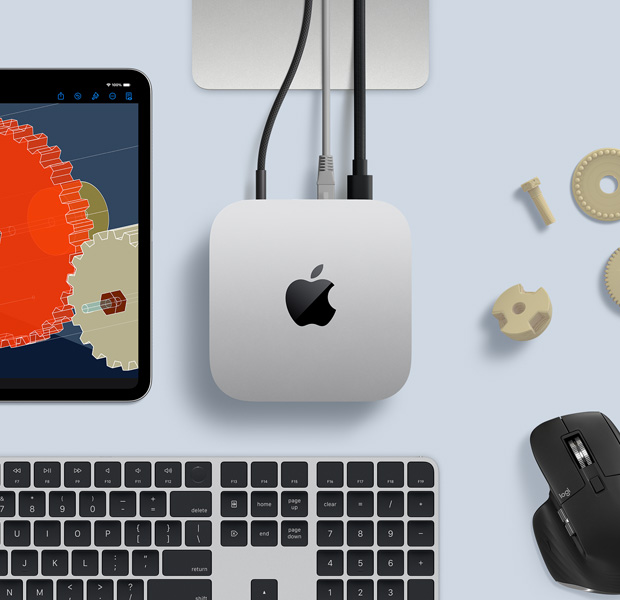 Pohled shora na stříbrný Mac mini v sestavě s černo‑stříbrnou bezdrátovou klávesnicí, černou bezdrátovou myší a iPadem